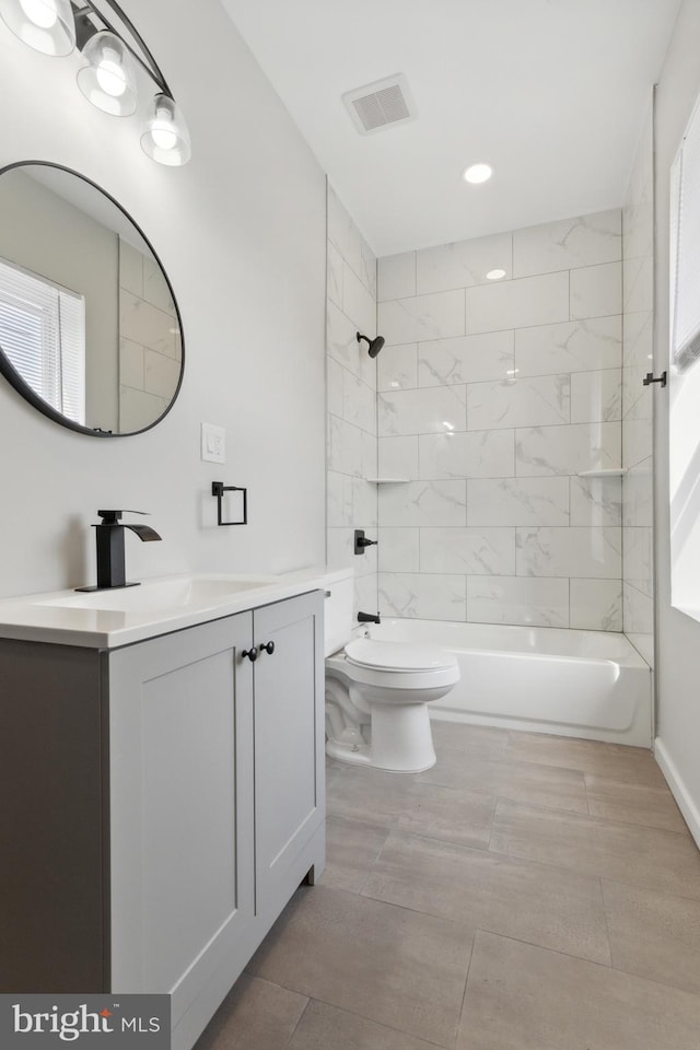 full bathroom featuring tiled shower / bath combo, vanity, and toilet