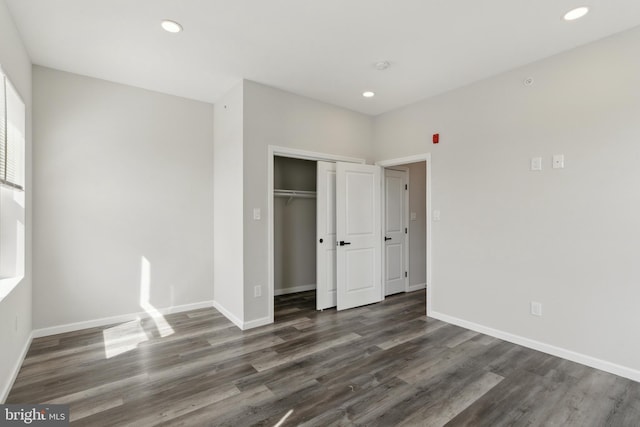 unfurnished bedroom with a closet and dark wood-type flooring