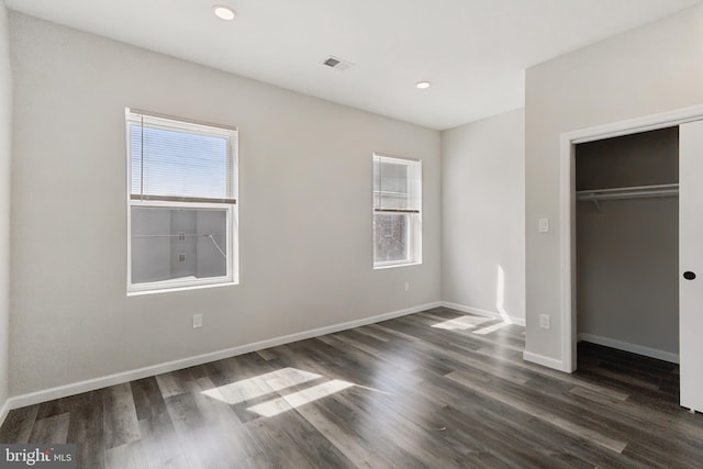 unfurnished bedroom with dark wood-type flooring and a closet