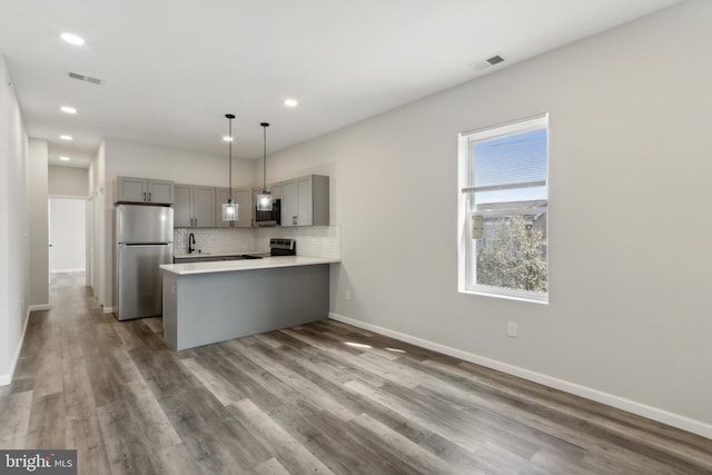 kitchen featuring sink, kitchen peninsula, gray cabinetry, stainless steel appliances, and dark hardwood / wood-style flooring