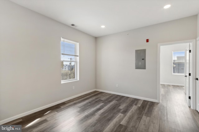 spare room with electric panel and dark hardwood / wood-style flooring