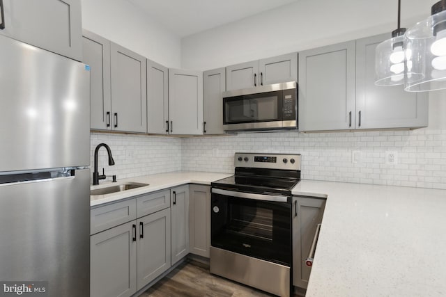 kitchen with dark wood-type flooring, tasteful backsplash, gray cabinets, stainless steel appliances, and sink