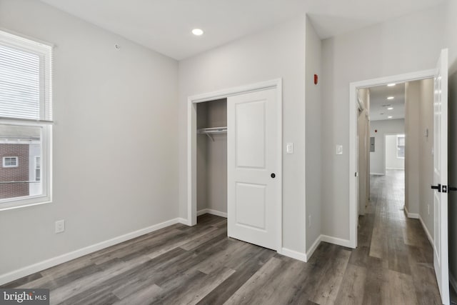 unfurnished bedroom with a closet, dark hardwood / wood-style floors, and multiple windows