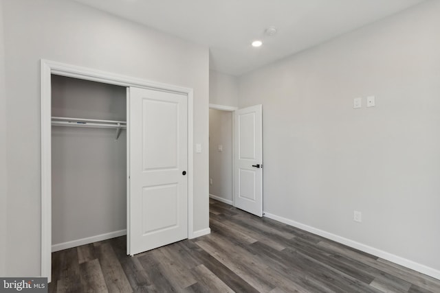 unfurnished bedroom with dark wood-type flooring and a closet