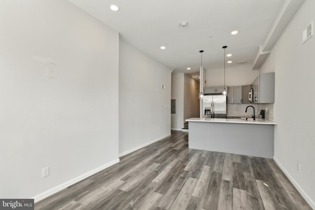 kitchen featuring stainless steel refrigerator with ice dispenser, kitchen peninsula, gray cabinetry, and dark hardwood / wood-style flooring