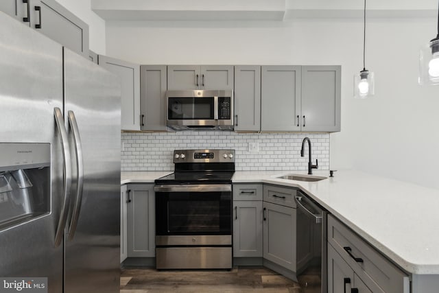 kitchen with pendant lighting, gray cabinets, dark wood-type flooring, sink, and stainless steel appliances