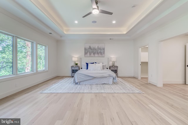 bedroom with a raised ceiling, light hardwood / wood-style floors, and ceiling fan