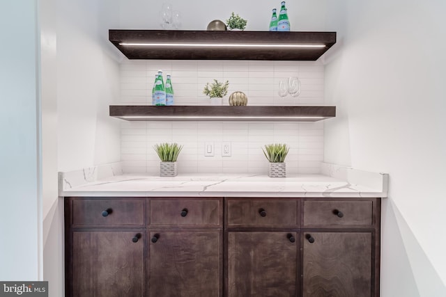 bar with dark brown cabinetry and tasteful backsplash