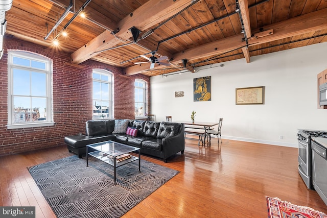 living room with a healthy amount of sunlight, wooden ceiling, brick wall, and rail lighting