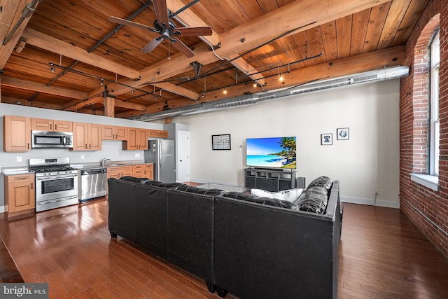 living room with dark wood-type flooring, brick wall, rail lighting, ceiling fan, and sink