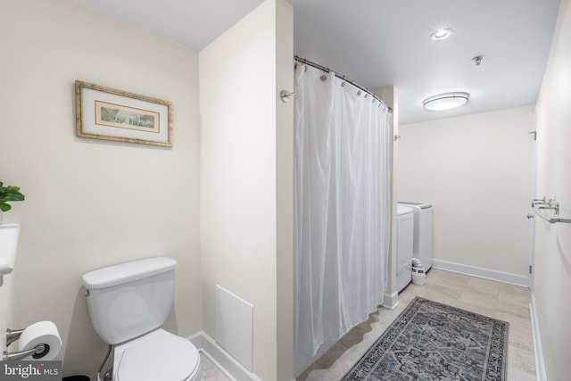 bathroom featuring washer and clothes dryer and toilet