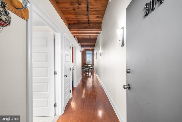 corridor featuring beamed ceiling, hardwood / wood-style flooring, and wooden ceiling