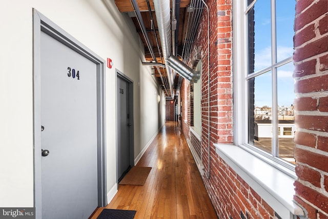 hallway featuring brick wall and hardwood / wood-style flooring