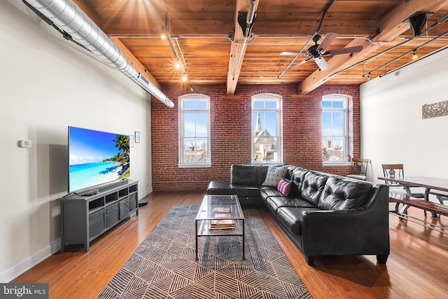 living room with brick wall, track lighting, wooden ceiling, and beamed ceiling