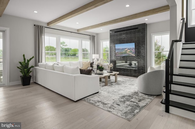 living room with beamed ceiling, a multi sided fireplace, a wealth of natural light, and light hardwood / wood-style flooring