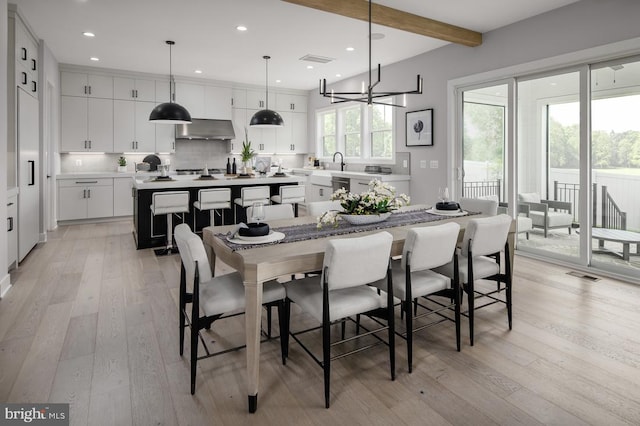 dining space with beam ceiling, sink, a notable chandelier, and light hardwood / wood-style floors