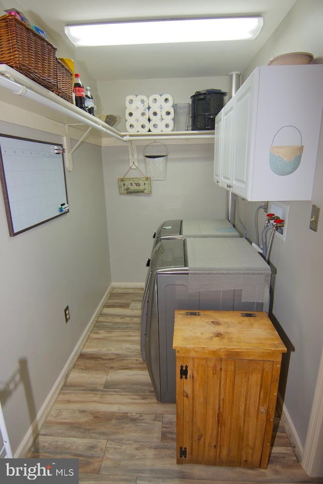 washroom with cabinets, light wood-type flooring, and washer and clothes dryer