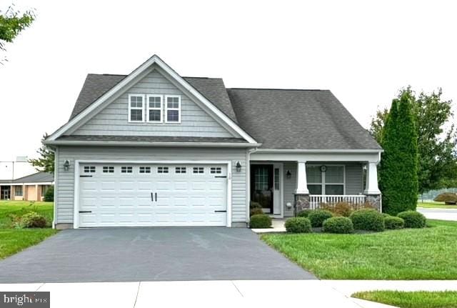 craftsman inspired home with a front lawn, a garage, and covered porch