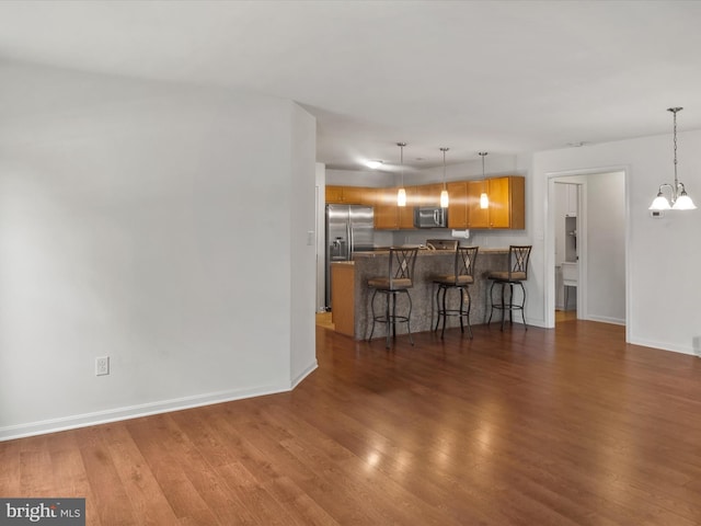 unfurnished living room with an inviting chandelier and dark hardwood / wood-style floors