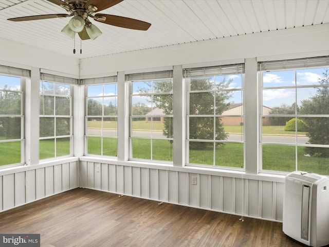 unfurnished sunroom featuring ceiling fan, wood ceiling, and a healthy amount of sunlight