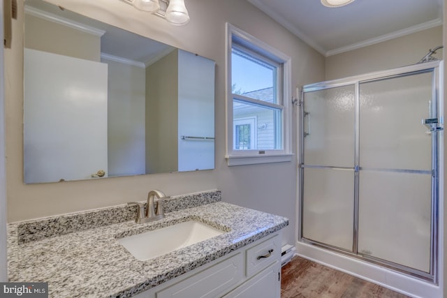 bathroom featuring crown molding, a shower with door, hardwood / wood-style flooring, and vanity