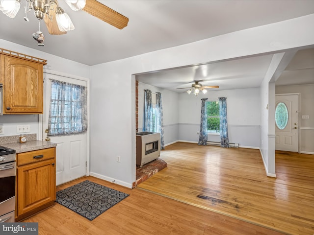 kitchen featuring baseboard heating, stainless steel electric stove, ceiling fan, and light hardwood / wood-style flooring