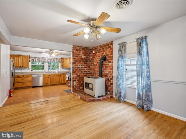 unfurnished living room featuring ceiling fan, heating unit, light hardwood / wood-style flooring, and a wood stove