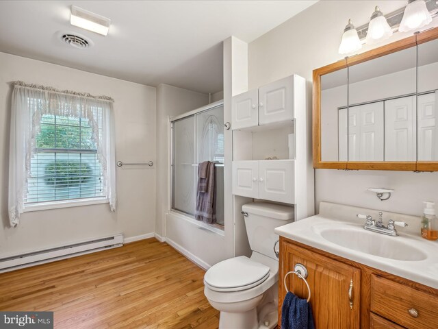 full bathroom featuring shower / bath combination with glass door, vanity, toilet, a baseboard heating unit, and hardwood / wood-style floors