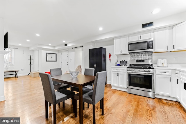 kitchen with light hardwood / wood-style flooring, stainless steel appliances, and white cabinetry