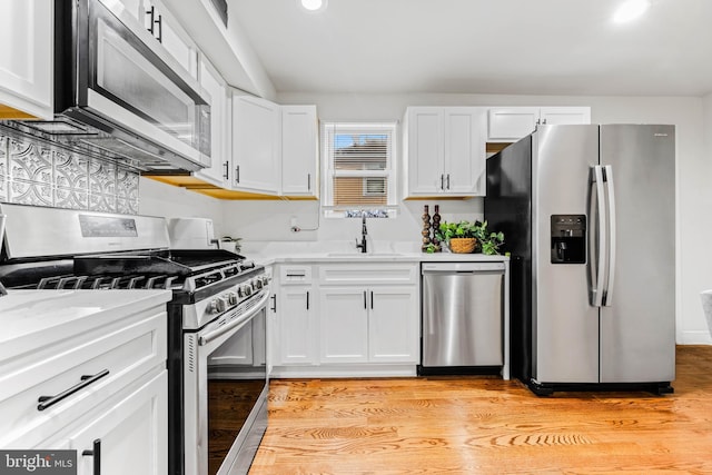 kitchen with light hardwood / wood-style floors, sink, stainless steel appliances, light stone countertops, and white cabinets