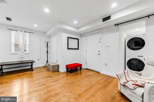 living area featuring stacked washer and clothes dryer and light wood-type flooring