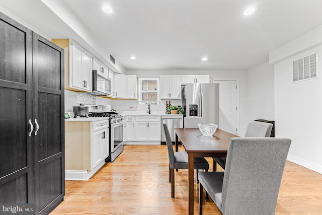 kitchen featuring stainless steel appliances, white cabinets, light hardwood / wood-style flooring, and sink