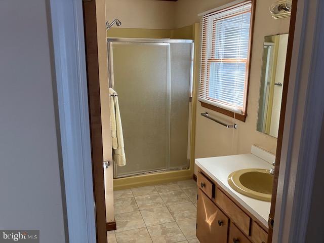 bathroom with a shower with door, vanity, and tile patterned floors