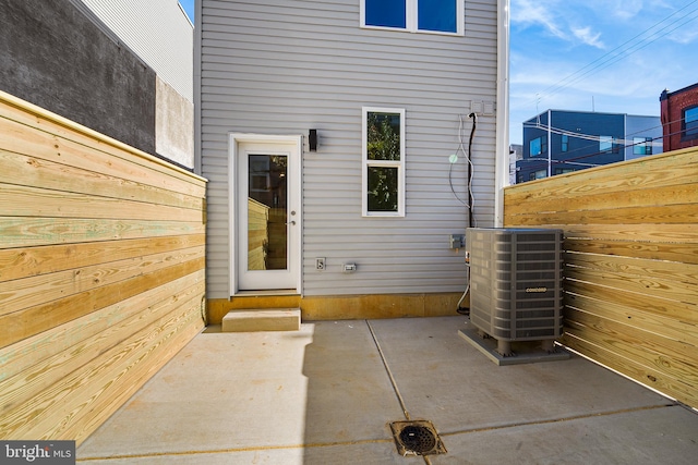 view of exterior entry with central AC unit and a patio area