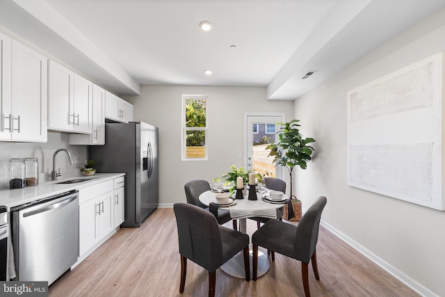 kitchen with sink, light hardwood / wood-style flooring, stainless steel appliances, and white cabinets