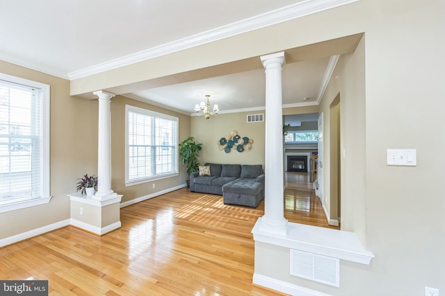 unfurnished living room with wood-type flooring, decorative columns, crown molding, and a wealth of natural light