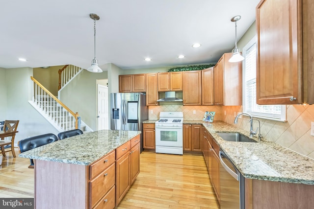 kitchen featuring a center island, appliances with stainless steel finishes, decorative light fixtures, and sink