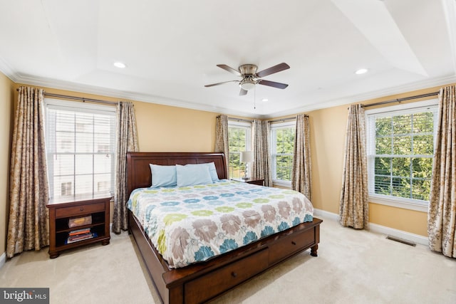 carpeted bedroom featuring ornamental molding, a tray ceiling, multiple windows, and ceiling fan