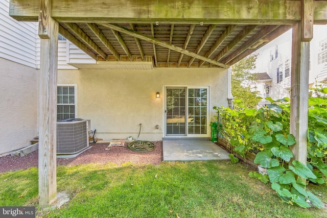 property entrance featuring cooling unit, a yard, and a patio area