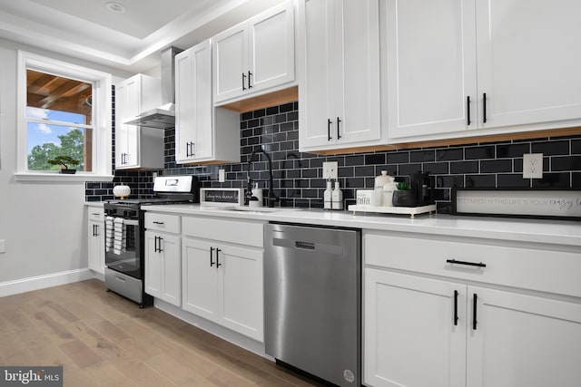 kitchen with stainless steel appliances, white cabinetry, light hardwood / wood-style floors, and tasteful backsplash