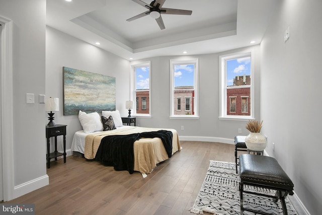 bedroom featuring wood-type flooring, a tray ceiling, and ceiling fan