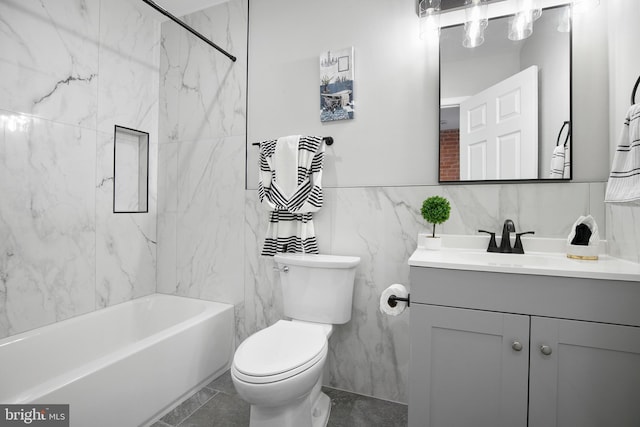 full bathroom featuring tile walls, tile patterned flooring, tiled shower / bath combo, vanity, and toilet