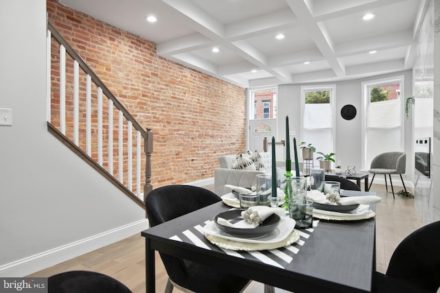 dining room with light hardwood / wood-style floors, coffered ceiling, beamed ceiling, and brick wall