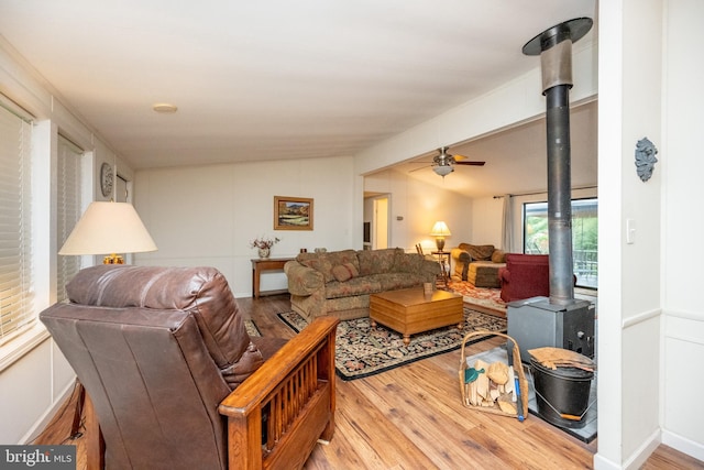 living room with hardwood / wood-style floors, ceiling fan, and a wood stove