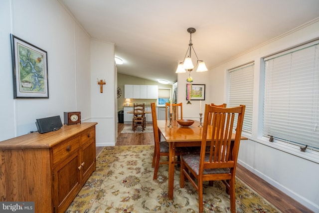 dining room featuring light wood-type flooring, crown molding, and lofted ceiling