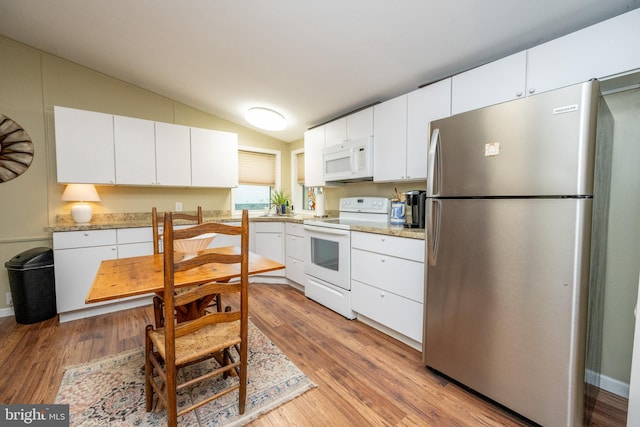 kitchen featuring lofted ceiling, white cabinets, and white appliances