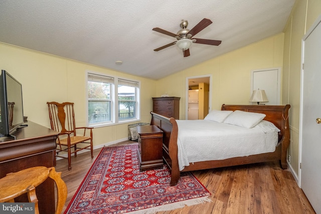 bedroom with lofted ceiling, a textured ceiling, and hardwood / wood-style floors