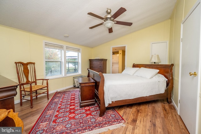 bedroom with a textured ceiling, vaulted ceiling, ceiling fan, and hardwood / wood-style flooring