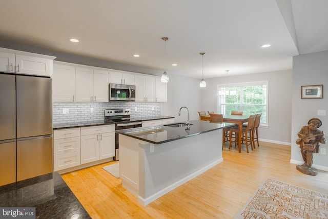 kitchen featuring decorative light fixtures, appliances with stainless steel finishes, sink, and white cabinetry