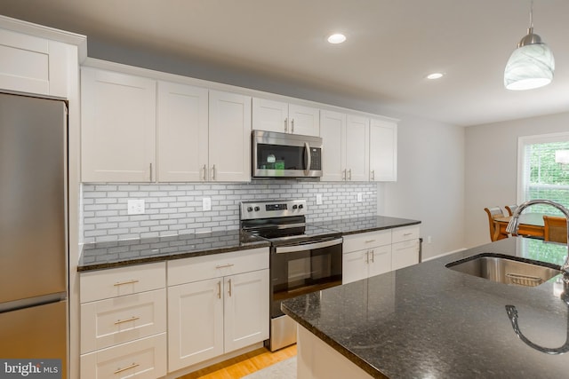 kitchen with sink, decorative light fixtures, white cabinetry, stainless steel appliances, and dark stone countertops